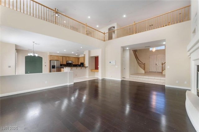 8901 Goldstone Ave, Las Vegas, NV 89143 - unfurnished living room featuring a high ceiling, wood finished floors, stairs, recessed lighting, and a glass covered fireplace