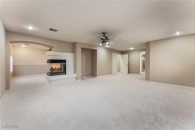 8901 Goldstone Ave, Las Vegas, NV 89143 - unfurnished living room with ceiling fan, a multi sided fireplace, light colored carpet, recessed lighting, and arched walkways