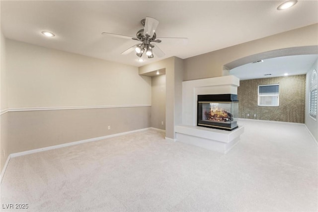 8901 Goldstone Ave, Las Vegas, NV 89143 - unfurnished living room with a multi sided fireplace, carpet floors, a ceiling fan, recessed lighting, and arched walkways