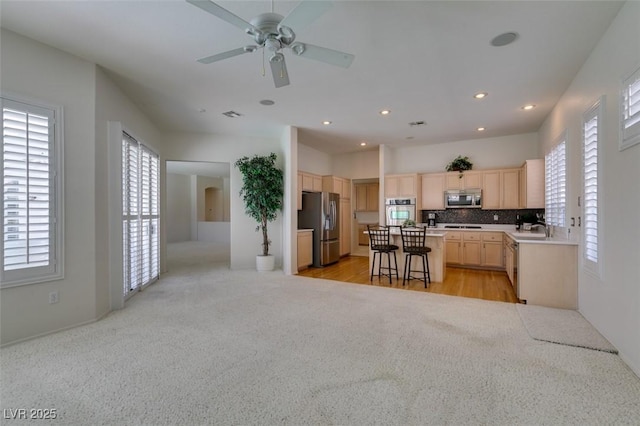 1414 Doggett Ave, Las Vegas, NV 89123 - kitchen featuring appliances with stainless steel finishes, light brown cabinetry, light carpet, ceiling fan, and tasteful backsplash