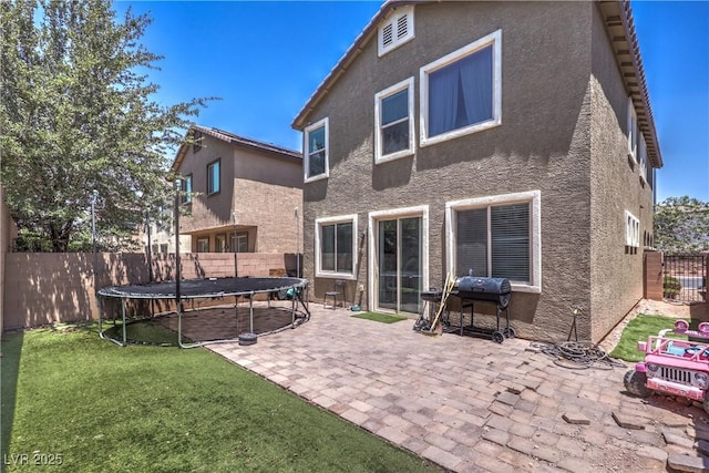 9237 S Chieftain St, Las Vegas, NV 89178 - back of house featuring a trampoline, stucco siding, a patio, and a fenced backyard