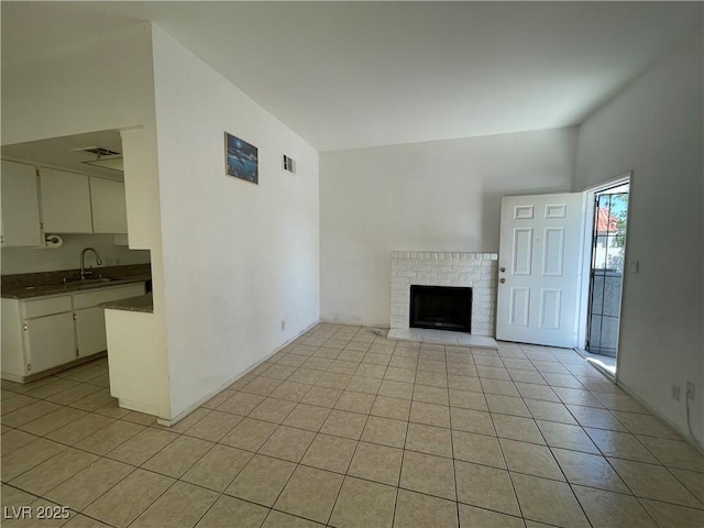 4320 Gannet Cir Unit 116, Las Vegas, NV 89103 - unfurnished living room featuring light tile patterned floors and a brick fireplace