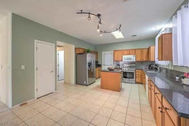 5209 Mantua Ct, Las Vegas, NV 89130 - kitchen with stainless steel appliances, a kitchen island, backsplash, light tile patterned flooring, and dark stone counters