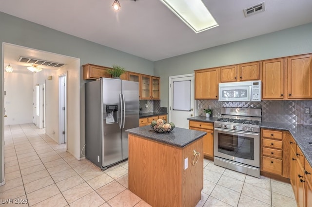 5209 Mantua Ct, Las Vegas, NV 89130 - kitchen with stainless steel appliances, a kitchen island, backsplash, light tile patterned floors, and brown cabinets