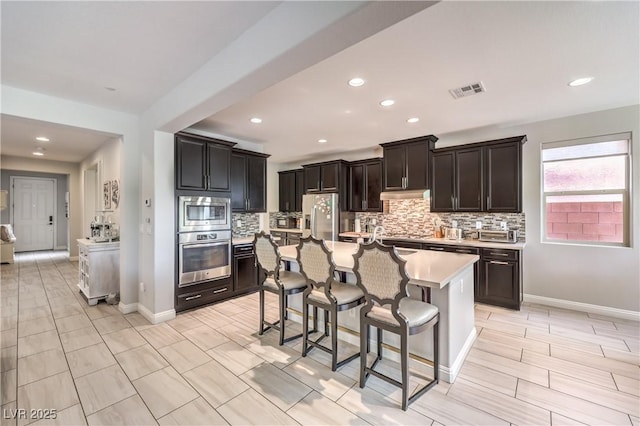 913 Silent Sunset Ave, North Las Vegas, NV 89084 - kitchen featuring appliances with stainless steel finishes, backsplash, light countertops, a kitchen bar, and recessed lighting