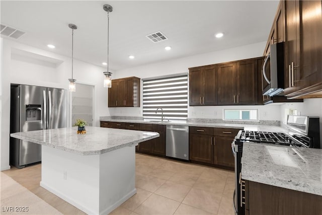 8144 Monsoon Bay St, Las Vegas, NV 89113 - kitchen with appliances with stainless steel finishes, dark brown cabinetry, light stone counters, hanging light fixtures, and a kitchen island