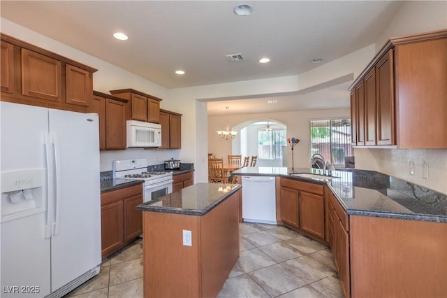 3813 Jasmine Heights Ave, North Las Vegas, NV 89081 - kitchen with white appliances, arched walkways, a chandelier, a peninsula, and brown cabinets