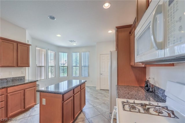 3813 Jasmine Heights Ave, North Las Vegas, NV 89081 - kitchen with white appliances, brown cabinets, a kitchen island, recessed lighting, and light tile patterned floors