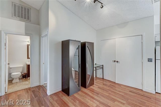1600 N Torrey Pines Dr Unit 202, Las Vegas, NV 89108 - unfurnished bedroom featuring light wood-style floors, connected bathroom, high vaulted ceiling, a textured ceiling, and a closet