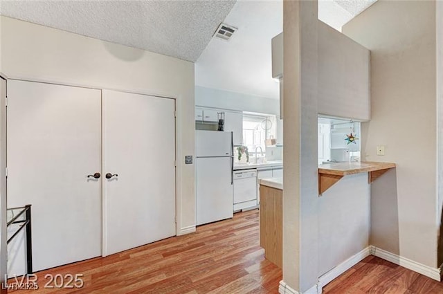 1600 N Torrey Pines Dr Unit 202, Las Vegas, NV 89108 - kitchen with white appliances, light wood finished floors, light countertops, a peninsula, and a breakfast bar area