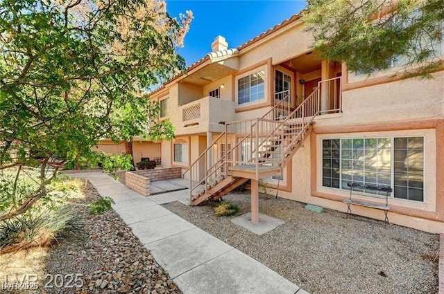1600 N Torrey Pines Dr Unit 202, Las Vegas, NV 89108 - back of property featuring a chimney, stucco siding, stairway, and a tiled roof
