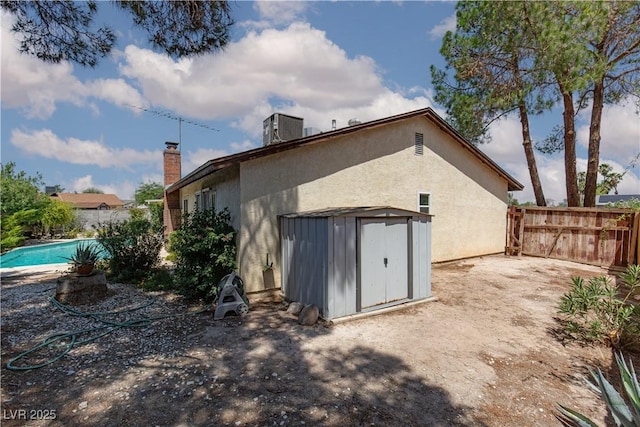 2157 Mccoig Ave, Las Vegas, NV 89119 - rear view of house with a storage shed, stucco siding, a chimney, and an outdoor pool