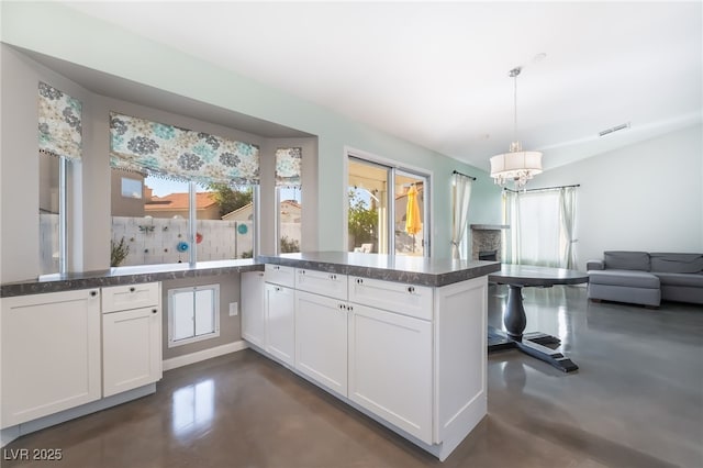 7048 Harbor View Dr, Las Vegas, NV 89119 - kitchen with finished concrete flooring, a chandelier, white cabinetry, and healthy amount of natural light