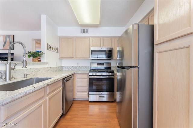5259 Caspian Springs Dr Unit 204, Las Vegas, NV 89120 - kitchen with light brown cabinetry, appliances with stainless steel finishes, light wood-style flooring, and light stone counters