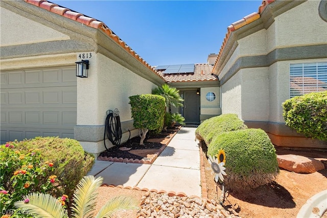 4813 W Virginia Falls Ln, Las Vegas, NV 89130 - property entrance featuring a tiled roof, roof mounted solar panels, stucco siding, and a garage