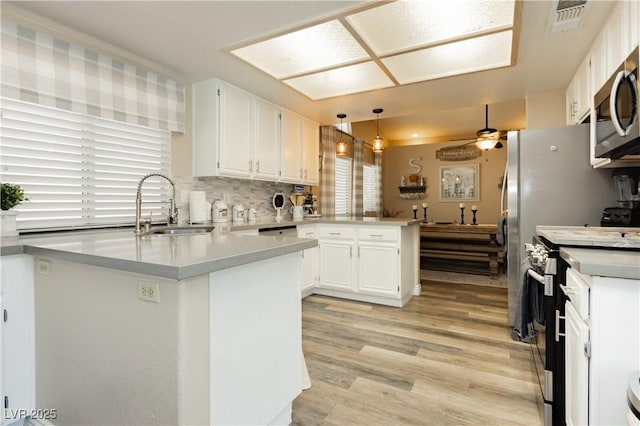 4813 W Virginia Falls Ln, Las Vegas, NV 89130 - kitchen featuring a peninsula, appliances with stainless steel finishes, white cabinets, light wood-type flooring, and light countertops
