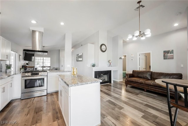 6552 Sweetzer Way, Las Vegas, NV 89108 - kitchen featuring stainless steel range with gas cooktop, wall chimney exhaust hood, open floor plan, light stone counters, and recessed lighting