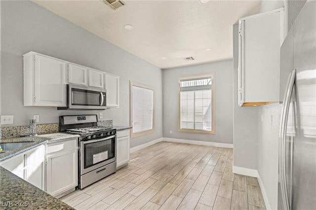 5616 Royal Castle Ln, Las Vegas, NV 89130 - kitchen featuring appliances with stainless steel finishes, white cabinetry, light stone countertops, light wood finished floors, and recessed lighting
