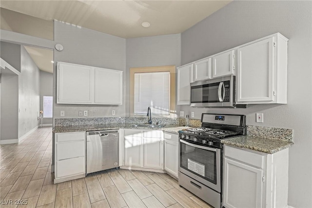 5616 Royal Castle Ln, Las Vegas, NV 89130 - kitchen featuring appliances with stainless steel finishes, white cabinetry, light stone countertops, and light wood finished floors