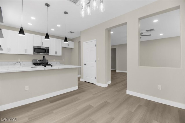 2118 High Mesa Dr, Henderson, NV 89012 - kitchen featuring stainless steel appliances, white cabinets, light wood-style flooring, pendant lighting, and ceiling fan