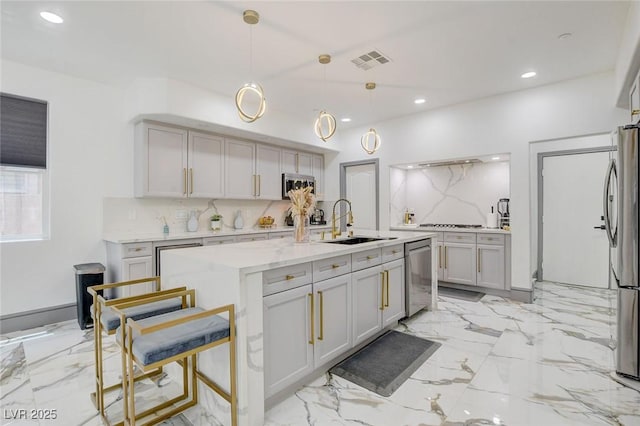 7024 Geese Gathering St, North Las Vegas, NV 89084 - kitchen with stainless steel appliances, decorative backsplash, recessed lighting, hanging light fixtures, and a center island with sink