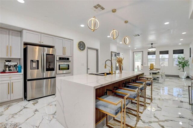 7024 Geese Gathering St, North Las Vegas, NV 89084 - kitchen with stainless steel appliances, light marble finish floors, recessed lighting, light stone counters, and a kitchen bar
