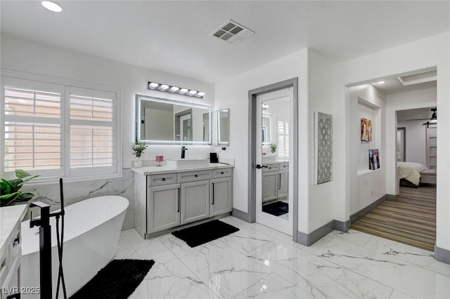 7024 Geese Gathering St, North Las Vegas, NV 89084 - bathroom featuring connected bathroom, vanity, a freestanding bath, marble look tiles, and recessed lighting