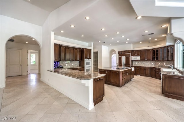 8021 Obannon Dr, Las Vegas, NV 89117 - kitchen with arched walkways, white appliances, light tile patterned floors, tasteful backsplash, and recessed lighting