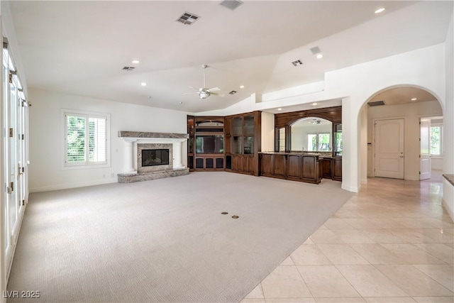 8021 Obannon Dr, Las Vegas, NV 89117 - unfurnished living room featuring arched walkways, ceiling fan, vaulted ceiling, a fireplace, and healthy amount of natural light