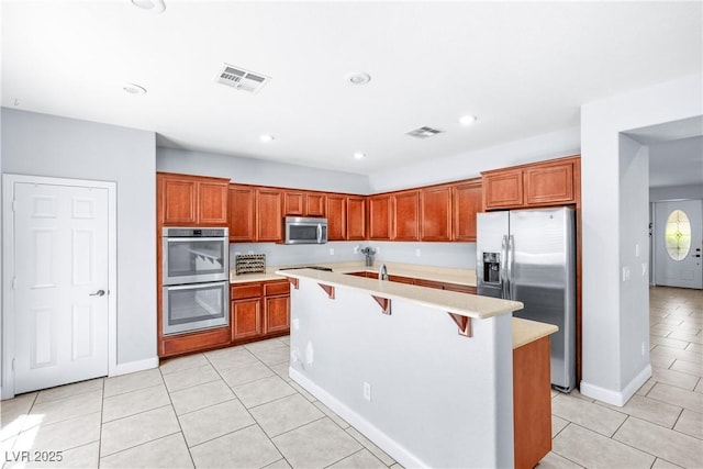 1141 Brent Park Ct, Henderson, NV 89002 - kitchen featuring appliances with stainless steel finishes, light tile patterned flooring, light countertops, a breakfast bar, and recessed lighting