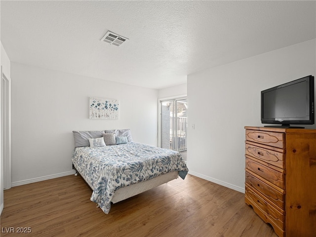 2214 Pebble Creek Ln, Laughlin, NV 89029 - bedroom featuring access to outside, wood finished floors, and a textured ceiling