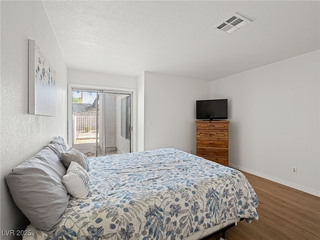 2214 Pebble Creek Ln, Laughlin, NV 89029 - bedroom with access to outside, wood finished floors, and a textured ceiling
