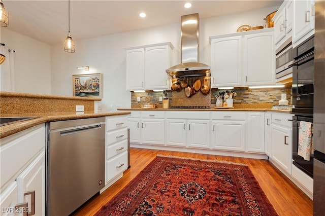 7209 Millerbird St, North Las Vegas, NV 89084 - kitchen featuring stainless steel appliances, wall chimney exhaust hood, recessed lighting, light wood-type flooring, and tasteful backsplash