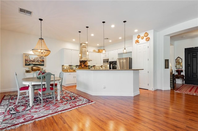 7209 Millerbird St, North Las Vegas, NV 89084 - kitchen with appliances with stainless steel finishes, wall chimney exhaust hood, light wood-style floors, white cabinets, and recessed lighting