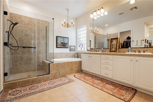 7209 Millerbird St, North Las Vegas, NV 89084 - bathroom with a chandelier, tile patterned floors, a stall shower, double vanity, and a garden tub