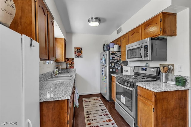 1037 Westminster Ave, Las Vegas, NV 89119 - kitchen with stainless steel appliances, dark wood-style floors, brown cabinetry, and backsplash