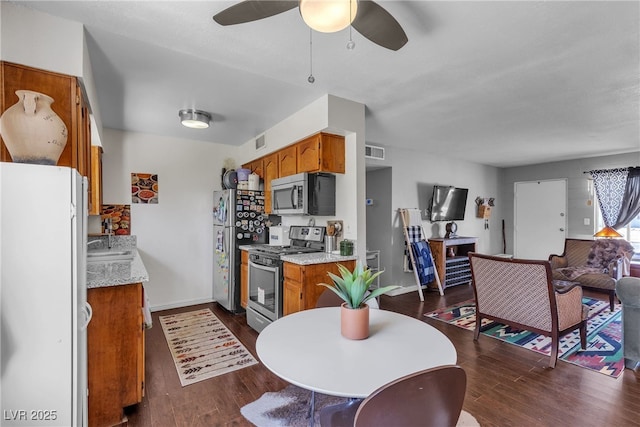 1037 Westminster Ave, Las Vegas, NV 89119 - kitchen with stainless steel appliances, dark wood-style flooring, brown cabinets, light countertops, and ceiling fan