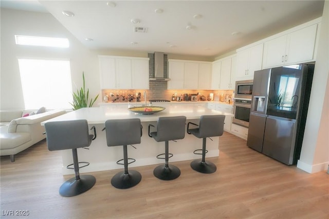 4182 Solace St, Las Vegas, NV 89135 - kitchen with appliances with stainless steel finishes, wall chimney exhaust hood, a breakfast bar, backsplash, and white cabinets