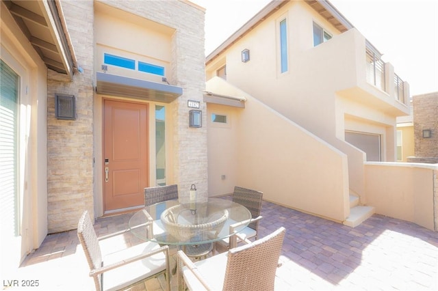 4182 Solace St, Las Vegas, NV 89135 - view of exterior entry featuring stucco siding, stone siding, outdoor dining space, and a patio area
