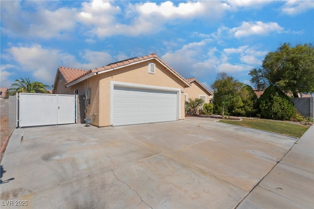 5243 Edna Crane Ave, North Las Vegas, NV 89031 - view of side of property with driveway, stucco siding, a tile roof, a gate, and a garage