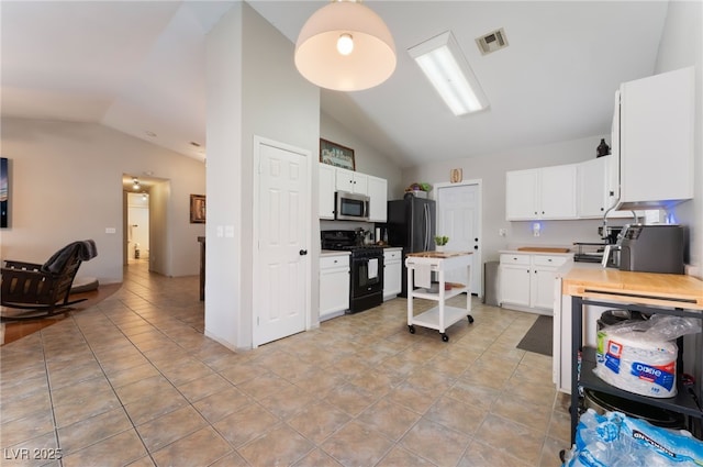 5243 Edna Crane Ave, North Las Vegas, NV 89031 - kitchen featuring gas stove, lofted ceiling, freestanding refrigerator, stainless steel microwave, and white cabinetry