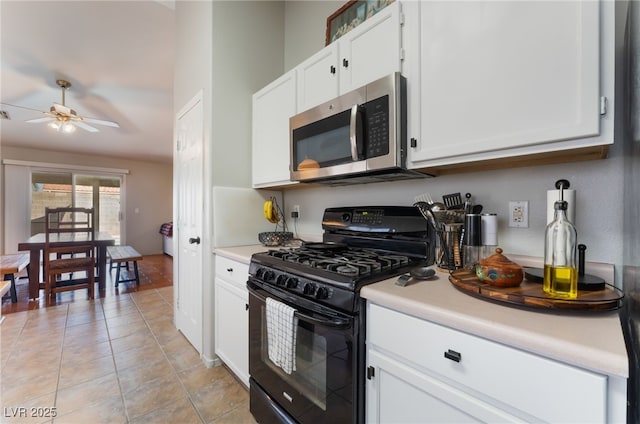 5243 Edna Crane Ave, North Las Vegas, NV 89031 - kitchen with stainless steel microwave, black gas range, light countertops, ceiling fan, and white cabinetry