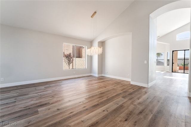 1016 Eaglewood Dr, Las Vegas, NV 89144 - unfurnished dining area featuring lofted ceiling, a chandelier, arched walkways, and wood finished floors