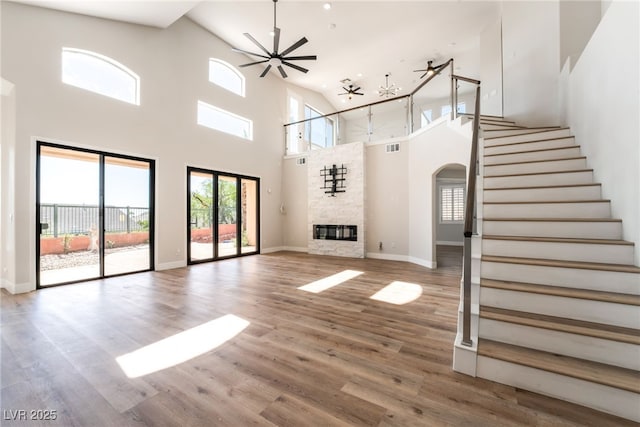 1016 Eaglewood Dr, Las Vegas, NV 89144 - unfurnished living room featuring a towering ceiling, arched walkways, ceiling fan, stairs, and wood finished floors