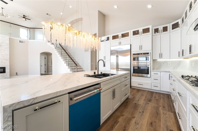 1016 Eaglewood Dr, Las Vegas, NV 89144 - kitchen with appliances with stainless steel finishes, a towering ceiling, arched walkways, ceiling fan, and light stone countertops