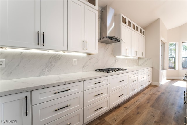 1016 Eaglewood Dr, Las Vegas, NV 89144 - kitchen with wall chimney range hood, stainless steel gas stovetop, tasteful backsplash, wood finished floors, and white cabinetry