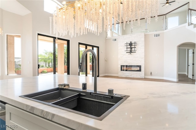 1016 Eaglewood Dr, Las Vegas, NV 89144 - kitchen with a towering ceiling, open floor plan, arched walkways, a stone fireplace, and light countertops