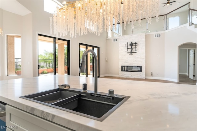 1016 Eaglewood Dr, Las Vegas, NV 89144 - kitchen with a towering ceiling, open floor plan, arched walkways, a chandelier, and a fireplace