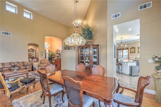 56 Ancient Hills Ln, Henderson, NV 89074 - dining space with a chandelier, a towering ceiling, arched walkways, and light wood-type flooring