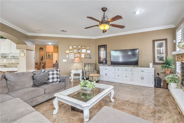 56 Ancient Hills Ln, Henderson, NV 89074 - living area featuring arched walkways, a ceiling fan, crown molding, and a fireplace with raised hearth